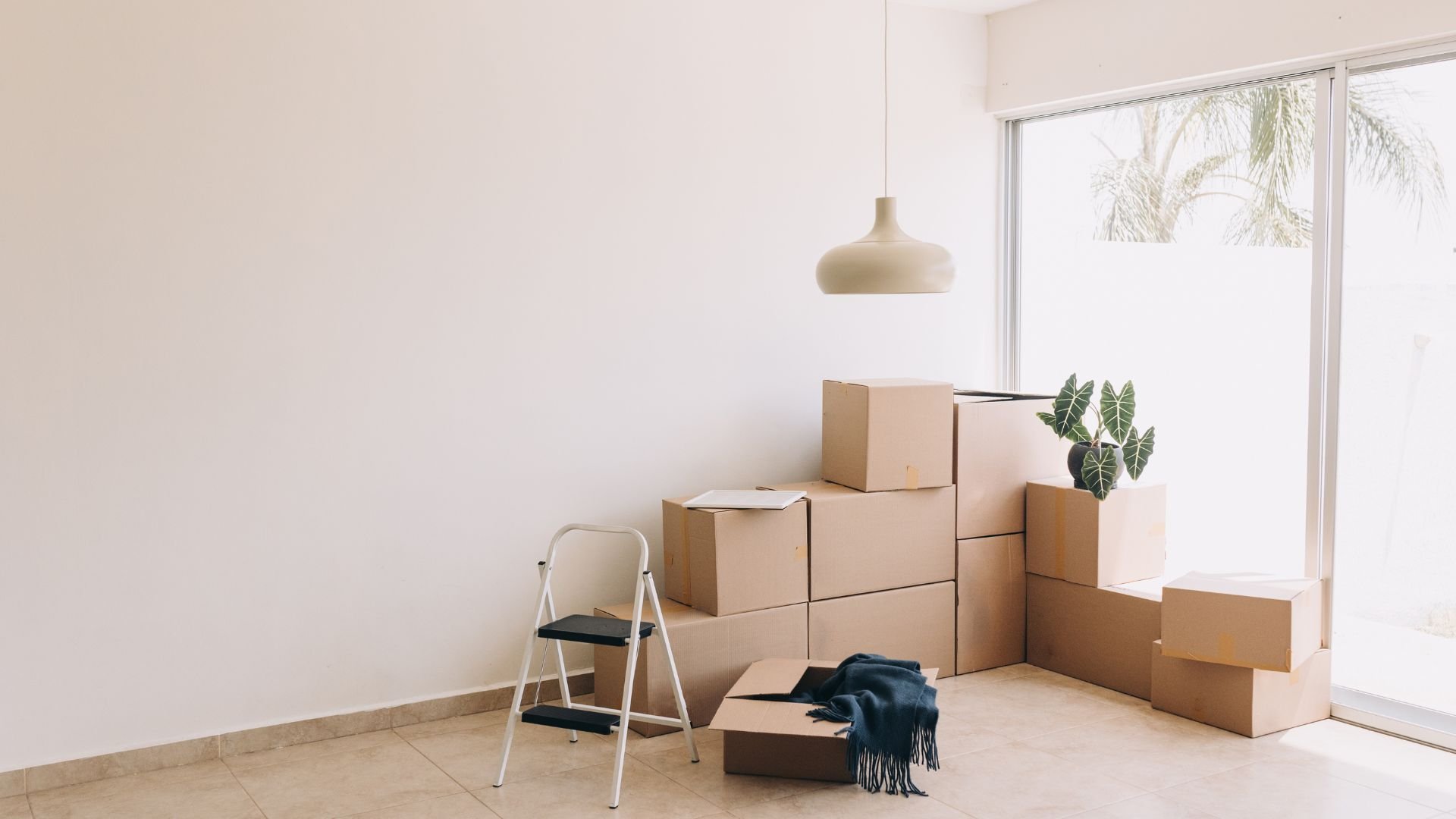 Moving boxes stacked in a minimalist room with a pendant lamp