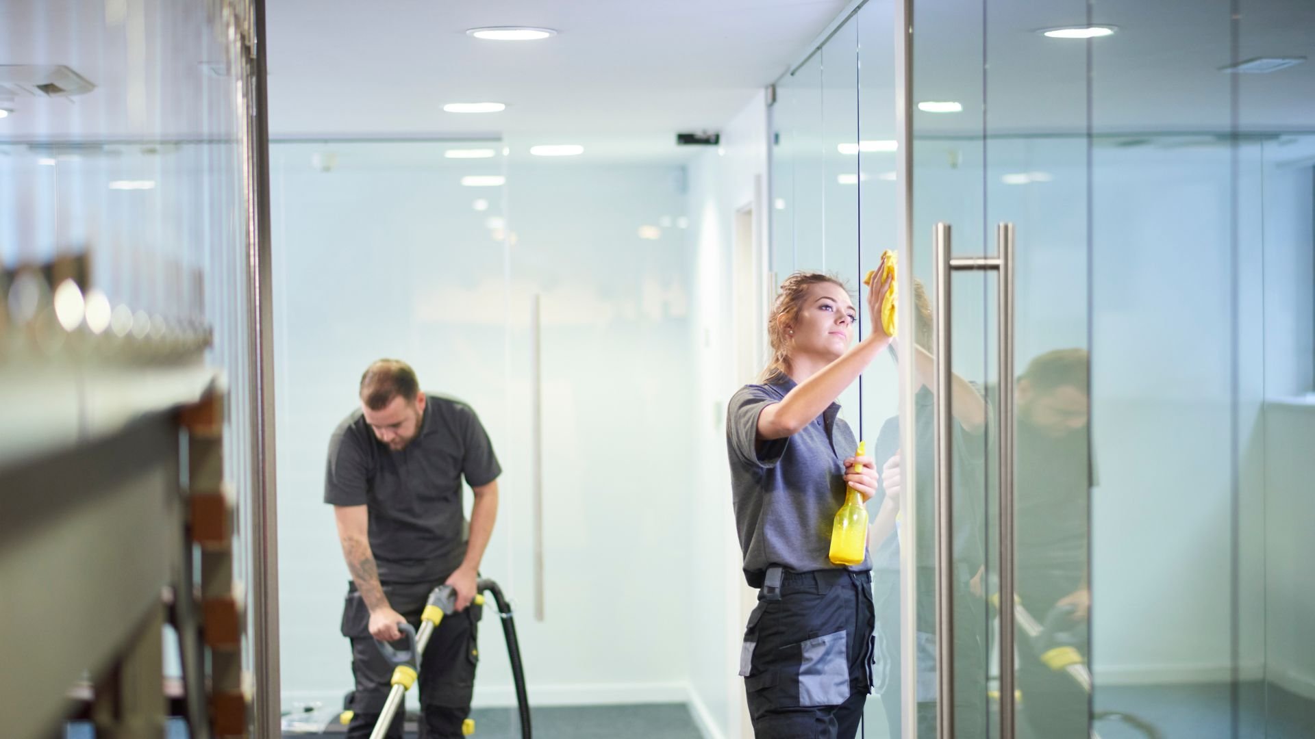 Professional cleaners working together to clean glass office interior