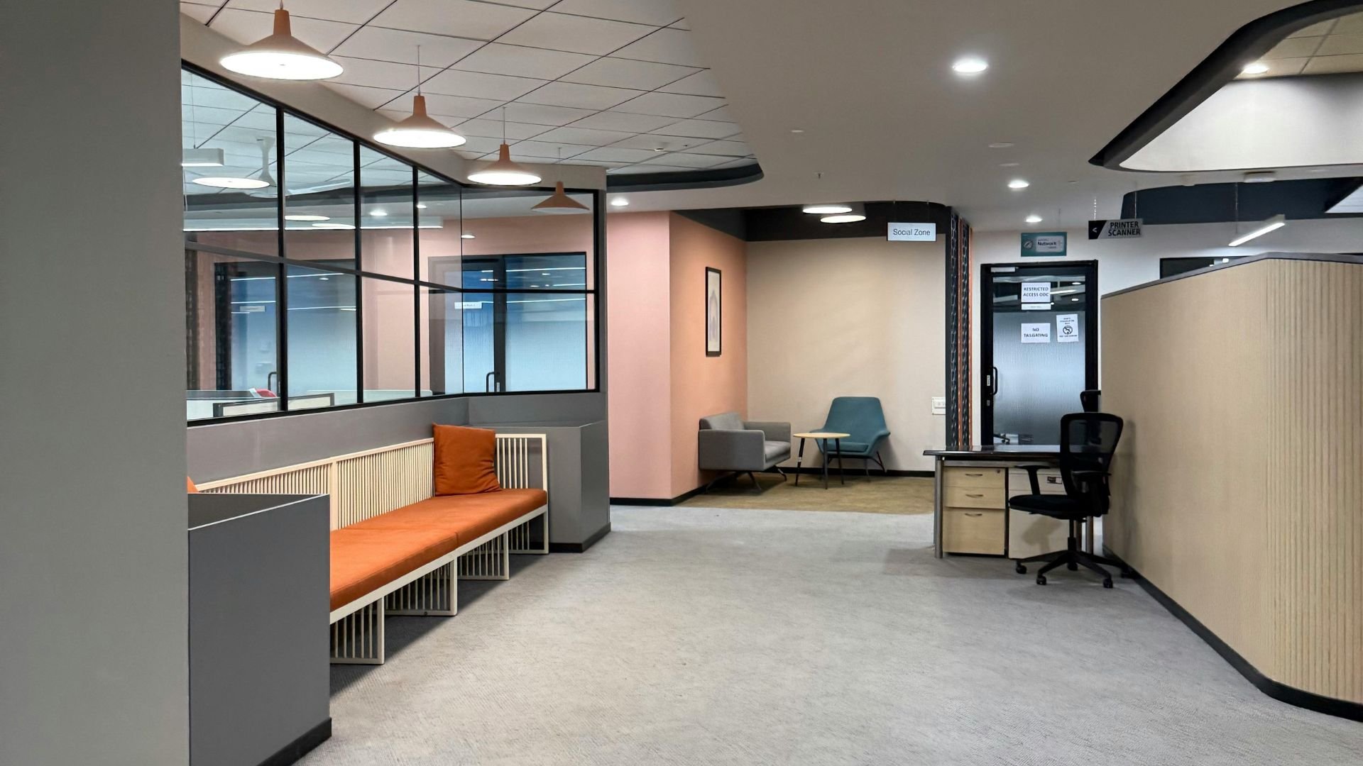Modern office interior with orange bench, glass walls, and social zone sign