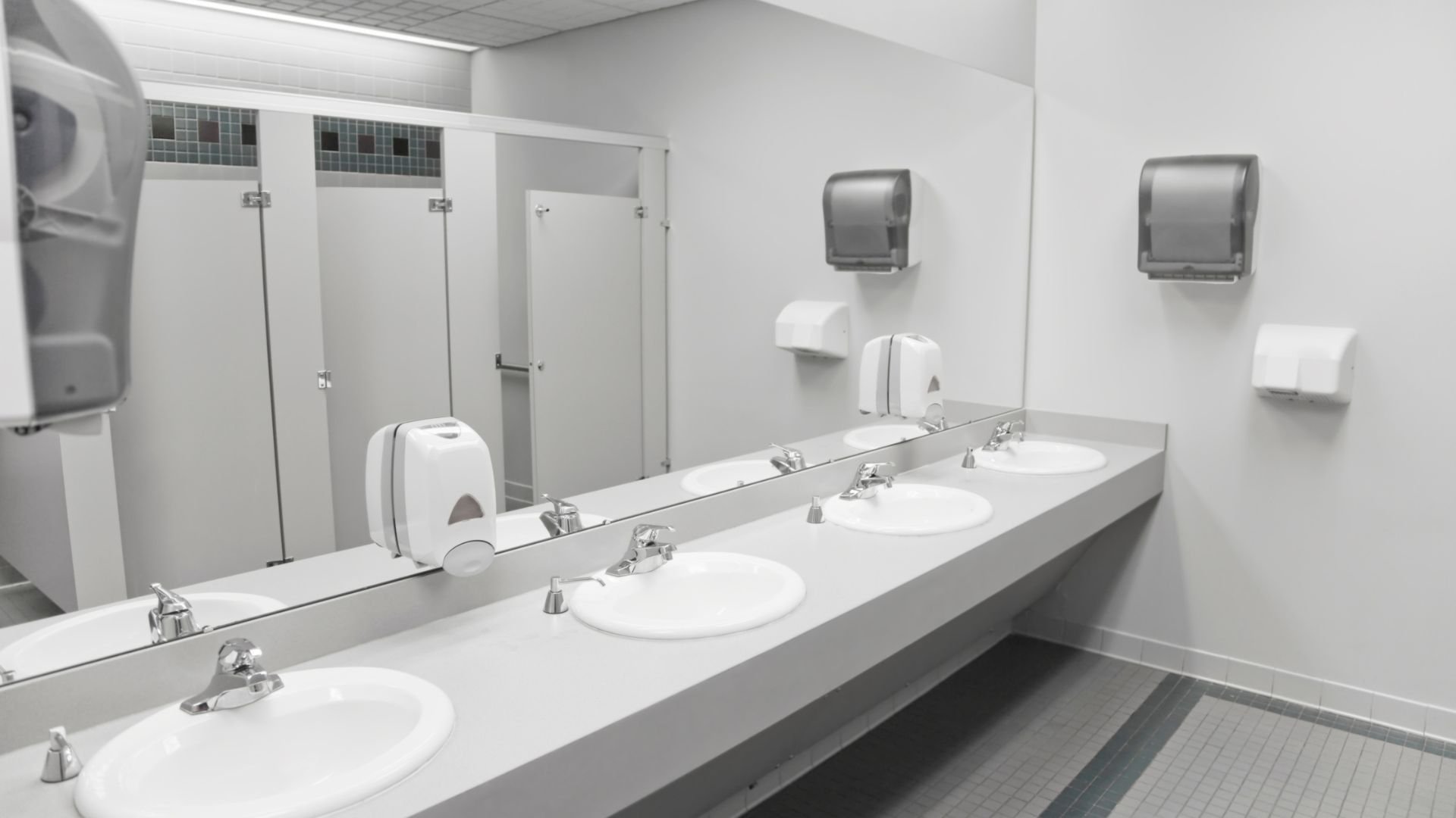 Clean public restroom with white sinks, mirrors, and paper towel dispensers